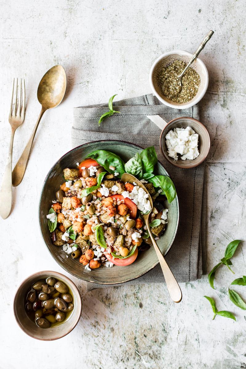 Ciotola con insalata di farro e ceci con basilico e pomodori e cucchiaiata di feta