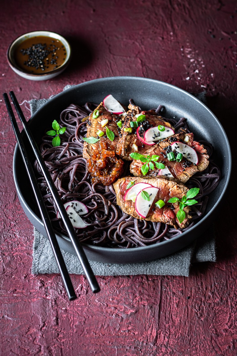 ciotola con noodle di riso nero e tataki di manzo