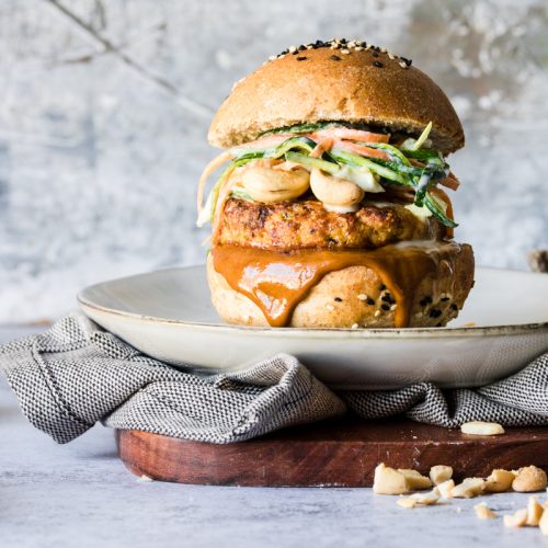 Burger di tacchino con salsa che cola su un piatto con sotto un tovagliolo e un tagliere