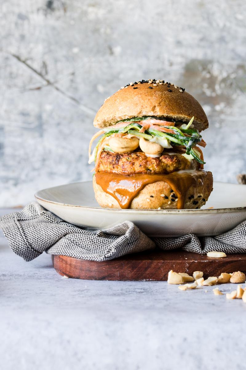 Burger di tacchino con salsa che cola su un piatto con sotto un tovagliolo e un tagliere