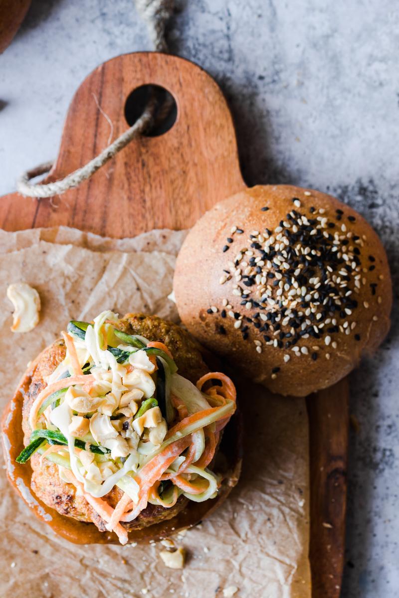 Tagliere con panino ai semi di sesamo aperto con burger di tacchino e coleslaw sopra