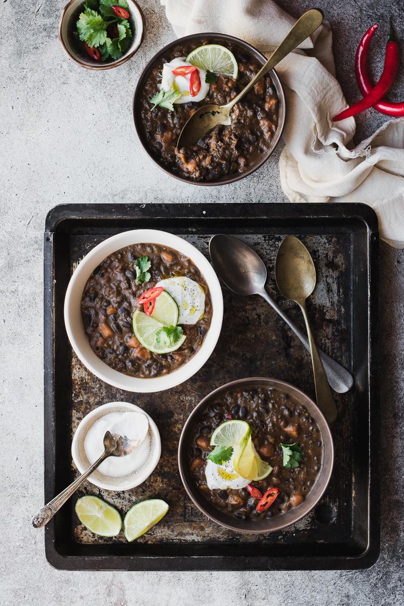 Ciotole di zuppa di fagioli neri e patata dolce con coriandolo e lime