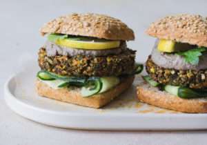 Due panini con veg burger di quinoa, patata dolce, fave con salsa tofu e olive visti di profilo