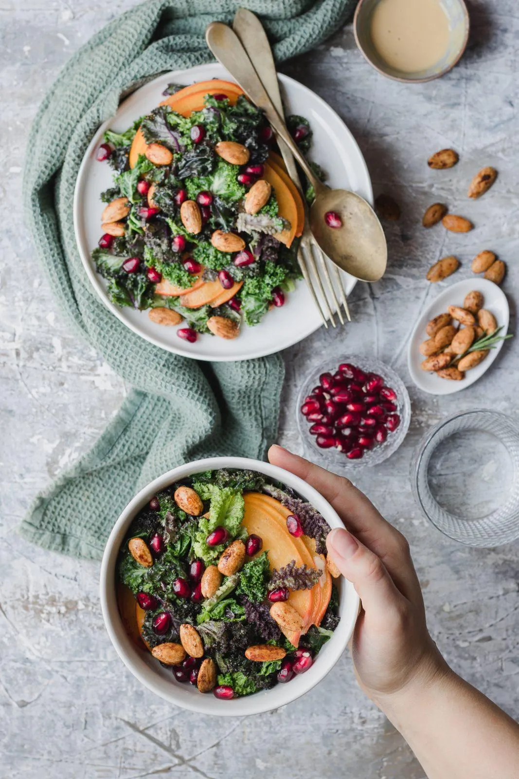 Due ciotole di insalata di kale e caco mela con mandorle croccanti e melograno