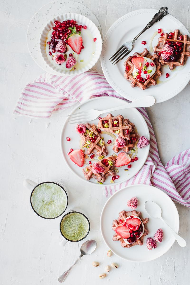 Waffle rosa con frutti rossi e due tazze di tè matcha