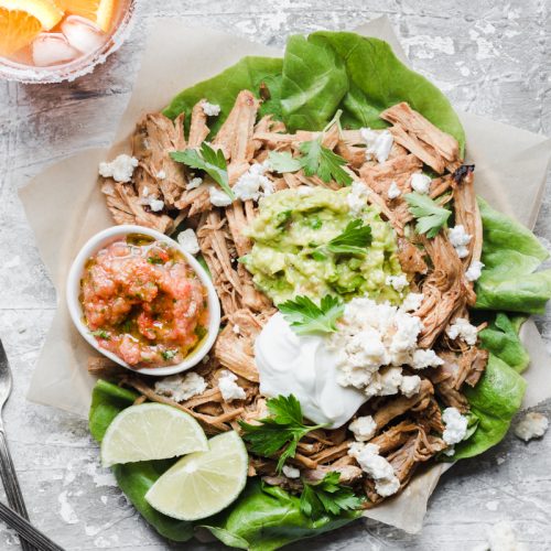 Carnitas plate with guacamole, sauce, queso, greek yogurt and lime with two glass of margaritas