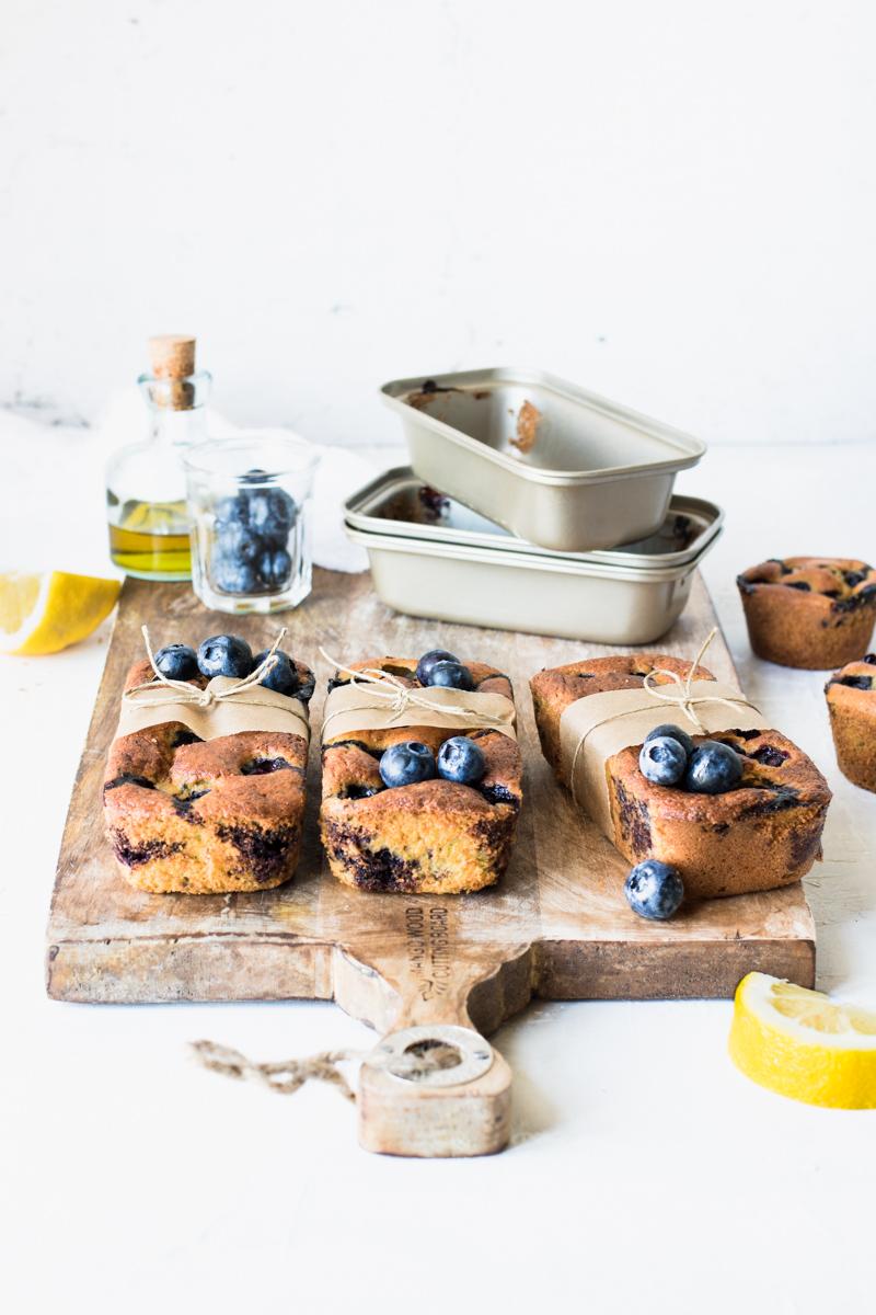 Mini plumcake ai mirtilli e limone con olio extravergine su un tagliere con gli stampi