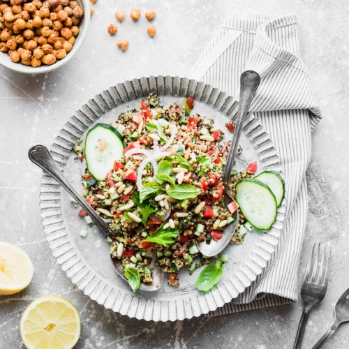 Piatto con due cucchiai e tabbuleh di quinoa tricolore, con ciotola di ceci arrosto