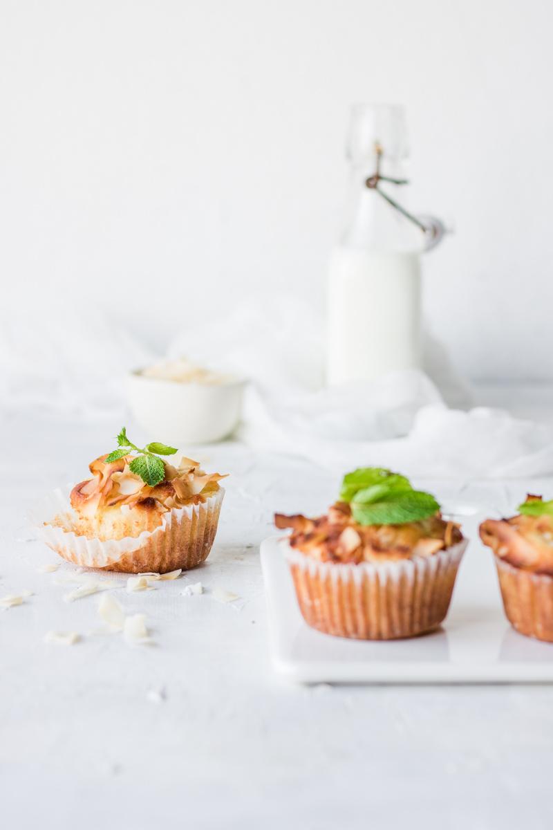 tre muffin nei pirottini di carta decorati con foglie di menta con una bottiglietta di vetro di latte sullo sfondo