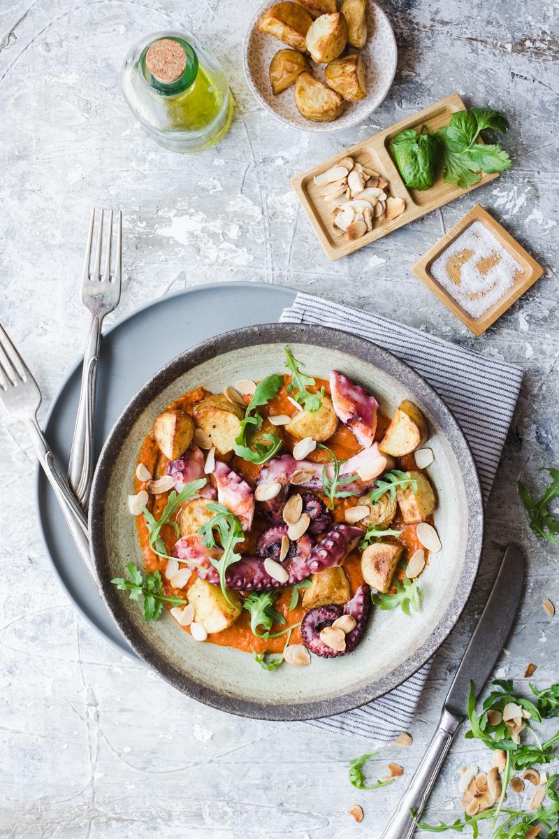 Piatto di polpo con patate arrosto, rucola e salsa romesco