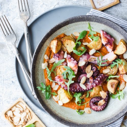 Piatto di polpo con patate arrosto, rucola e salsa romesco