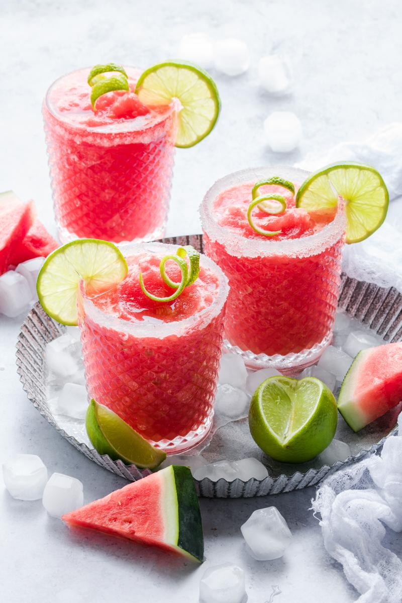 Tre bicchieri di virgin frozen margarita all'anguria con fette di lime come decorazione