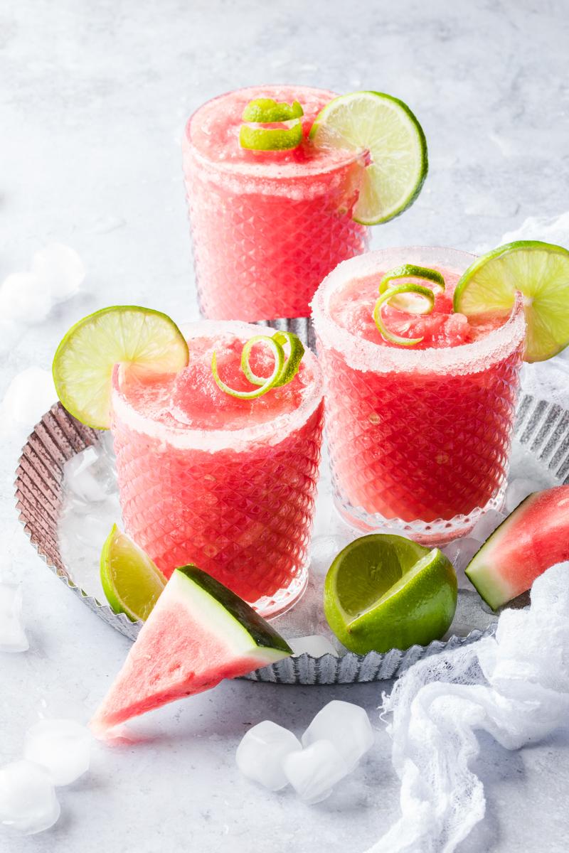 Tre bicchieri di virgin frozen margarita all'anguria con fette di lime come decorazione