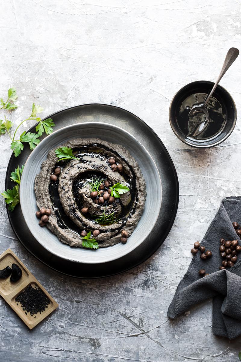 ciotola di hummus nero con foglie di prezzemolo