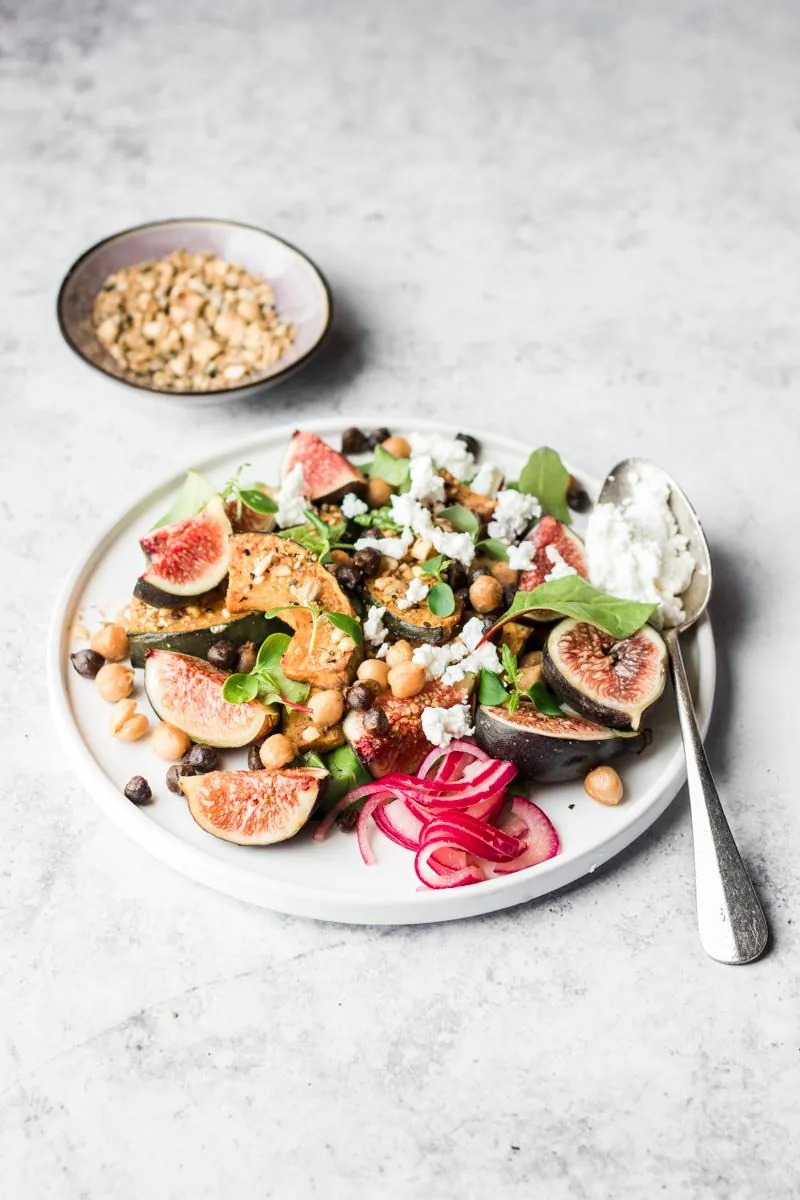 Piatto con Insalata di fichi con zucca alla dukkah e ceci, barattolo con cipolle sott'aceto e cucchiaio di ricotta