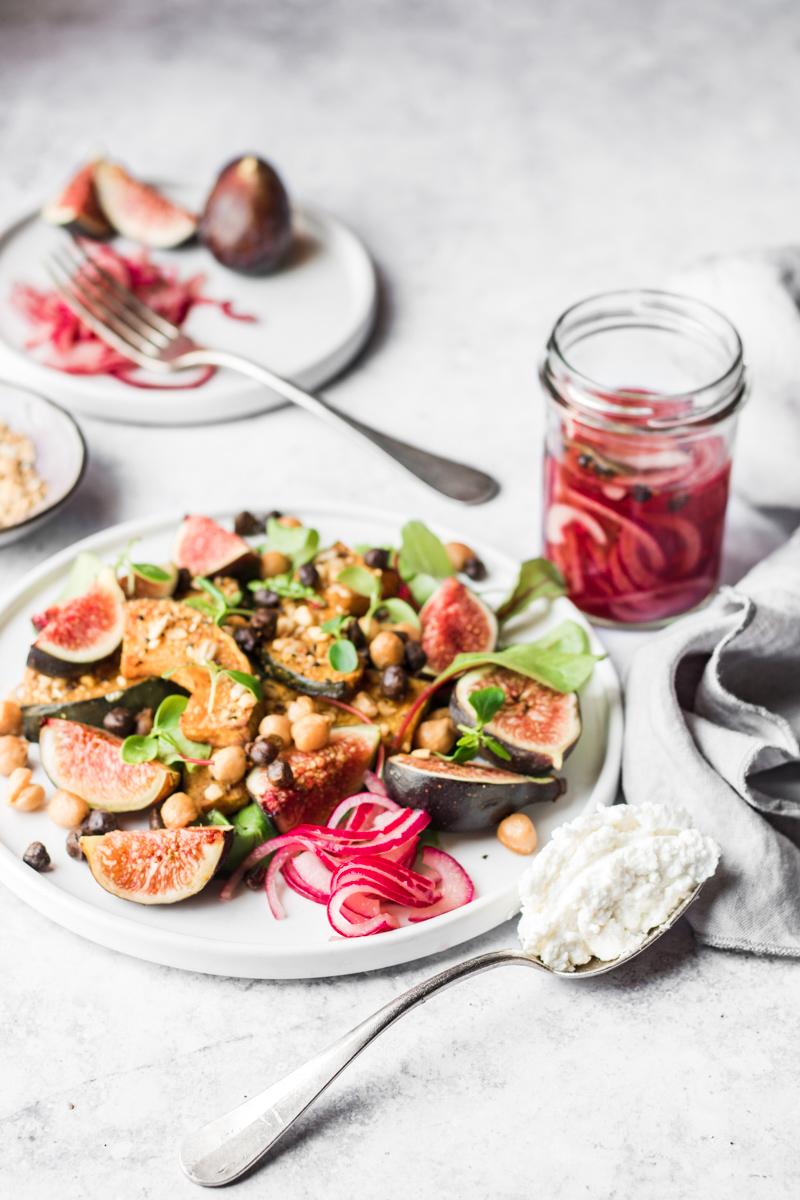 Piatto con Insalata di fichi con zucca alla dukkah e ceci, barattolo con cipolle sott'aceto e cucchiaio di ricotta