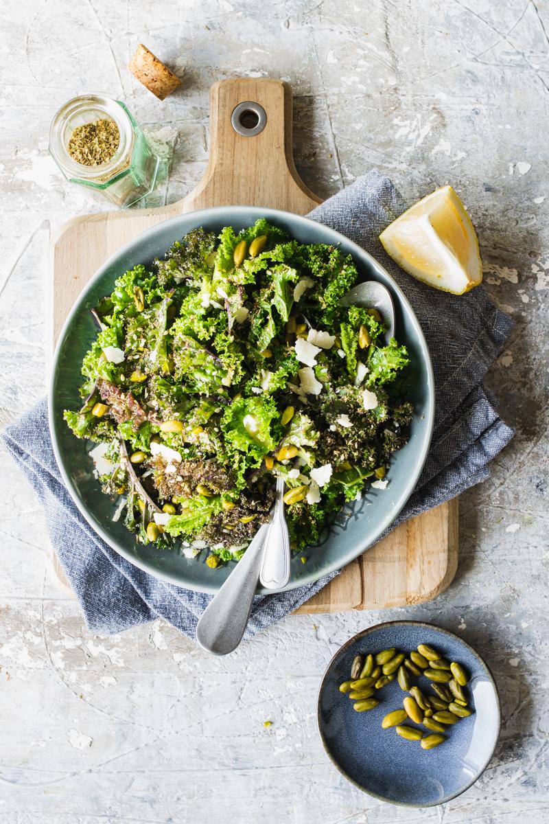 Piatto con insalata di kale o cavolo riccio su tagliere con limone e pistacchi in una ciotolina 