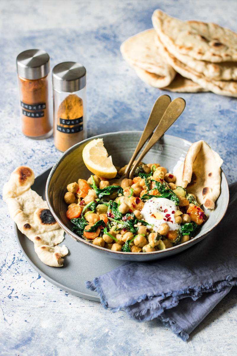 Ciotola con curry di spinaci e ceci accompagnato da pezzi di naan 