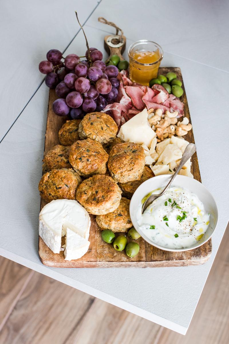 tagliere comn scones salati salumi, formaggi, uva e ciotola con panna acida