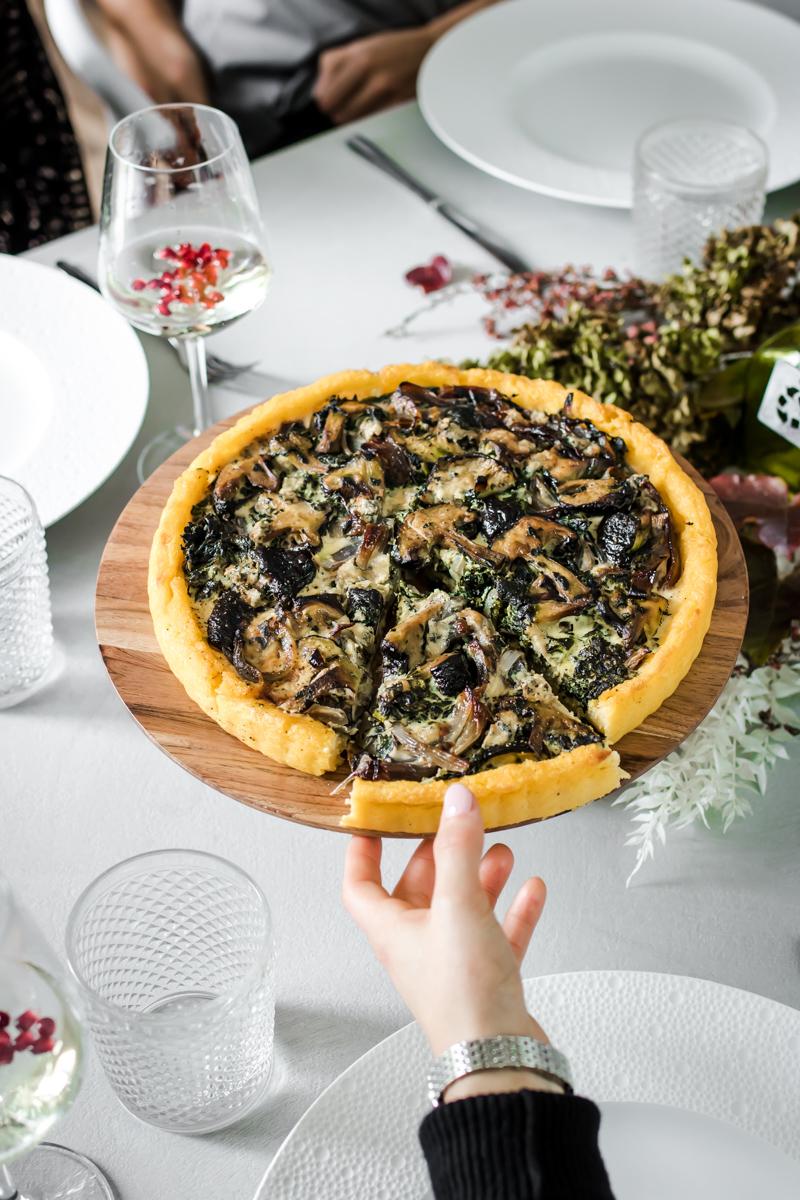 alzatina con tart di polenta ripiena di verdure e una mano che ne prende una fetta