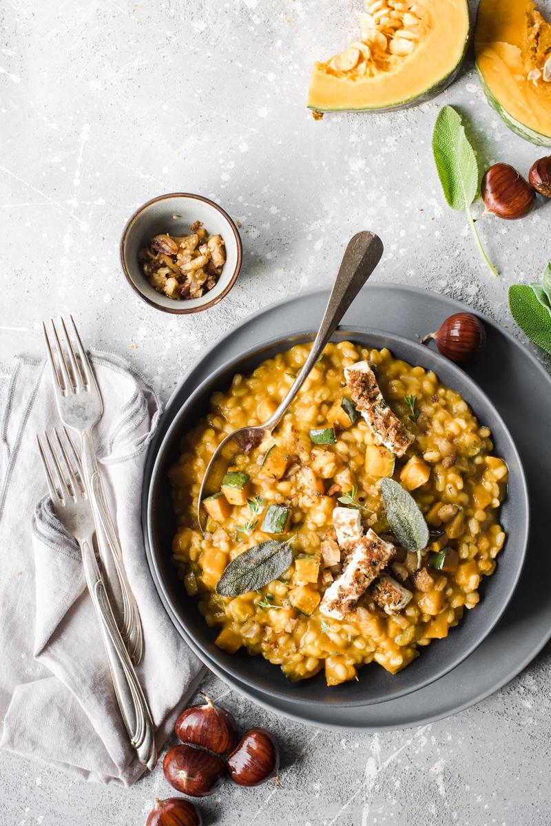 Piatto di orzotto alla zucca e castangne con primosale e foglie di salvia, con due forchette accanto