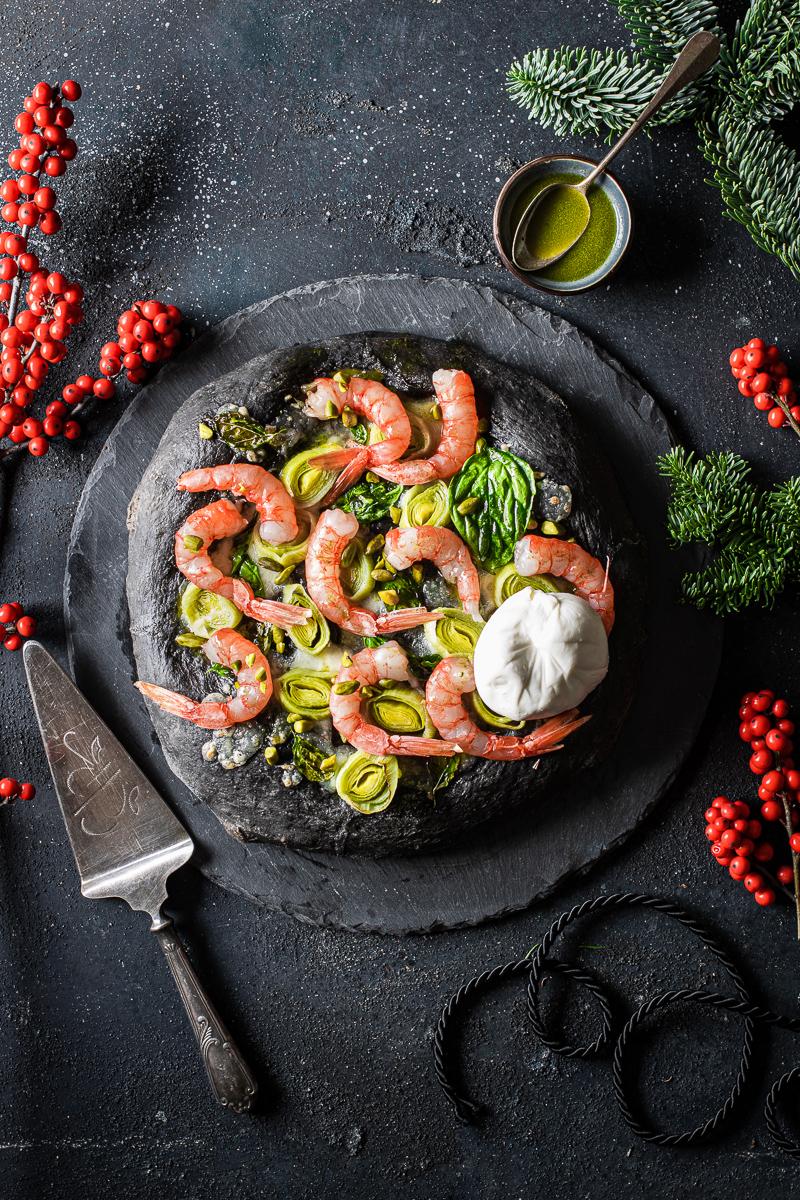 Piatto di ardesia con focaccia al nero di seppia, gamberi rossi e burrata