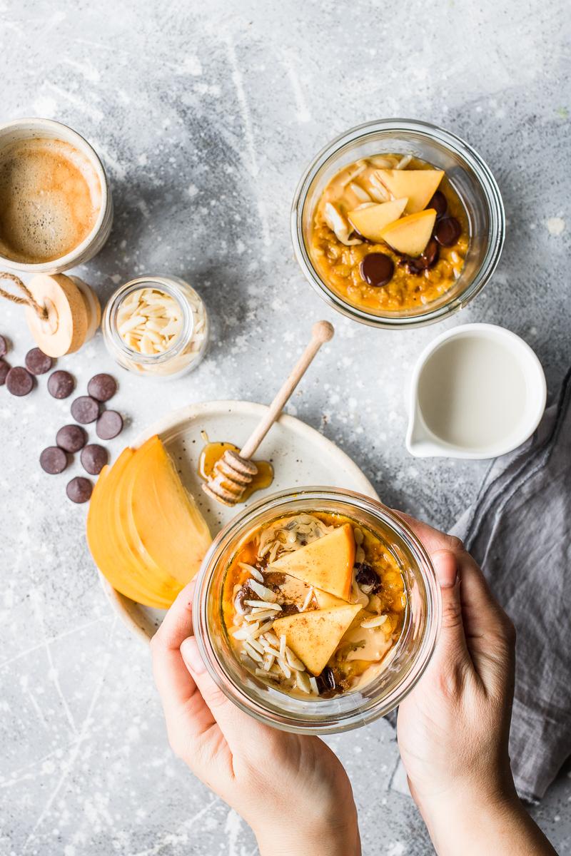 Tavola per la colazione con porridge alla zucca in vasocottura vegano cioccolato e cachi mela