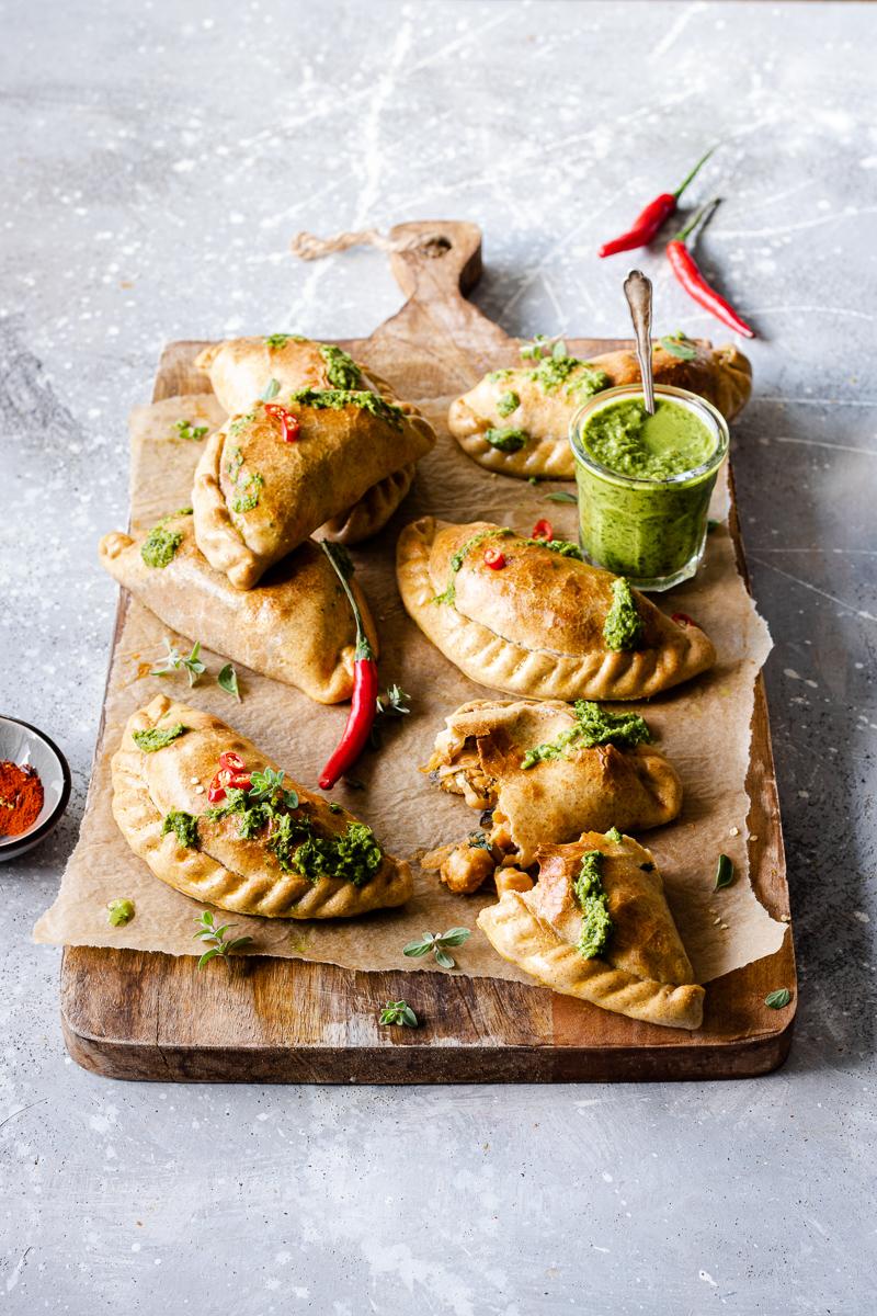 Tagliere di legno con empanadas vegetariane al forno e salsa chimichurri