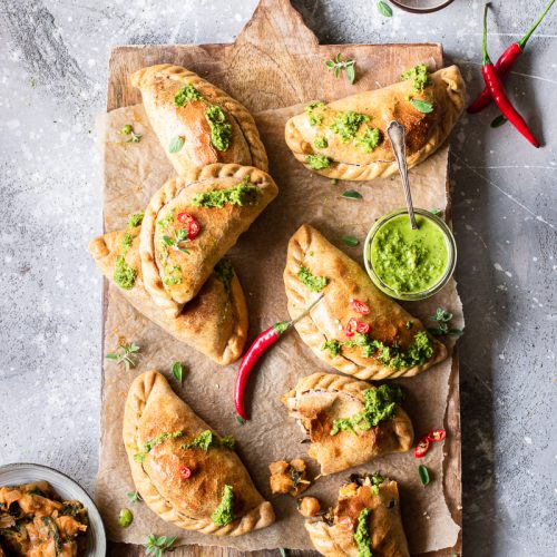 Tagliere di legno con empanadas vegetariane al forno e salsa chimichurri