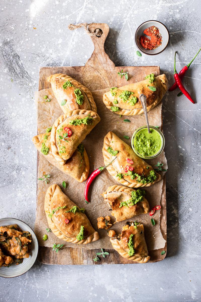 Tagliere di legno con empanadas vegetariane al forno e salsa chimichurri