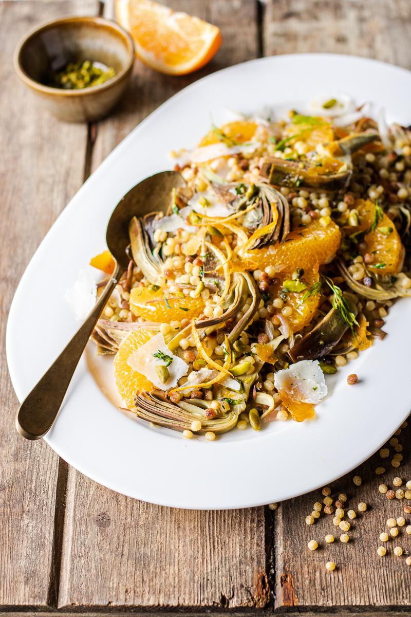 Vassoio bianco con insalata di fregola con carciofi, arancia, bottarga, pecorino e pistacchi