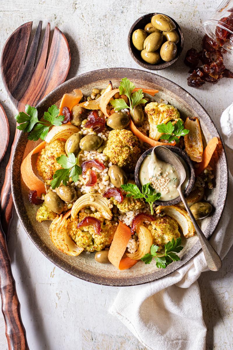 Insalata di cavolfiore arrosto con bulgur, fagioli, datteri e carote in una ciotola