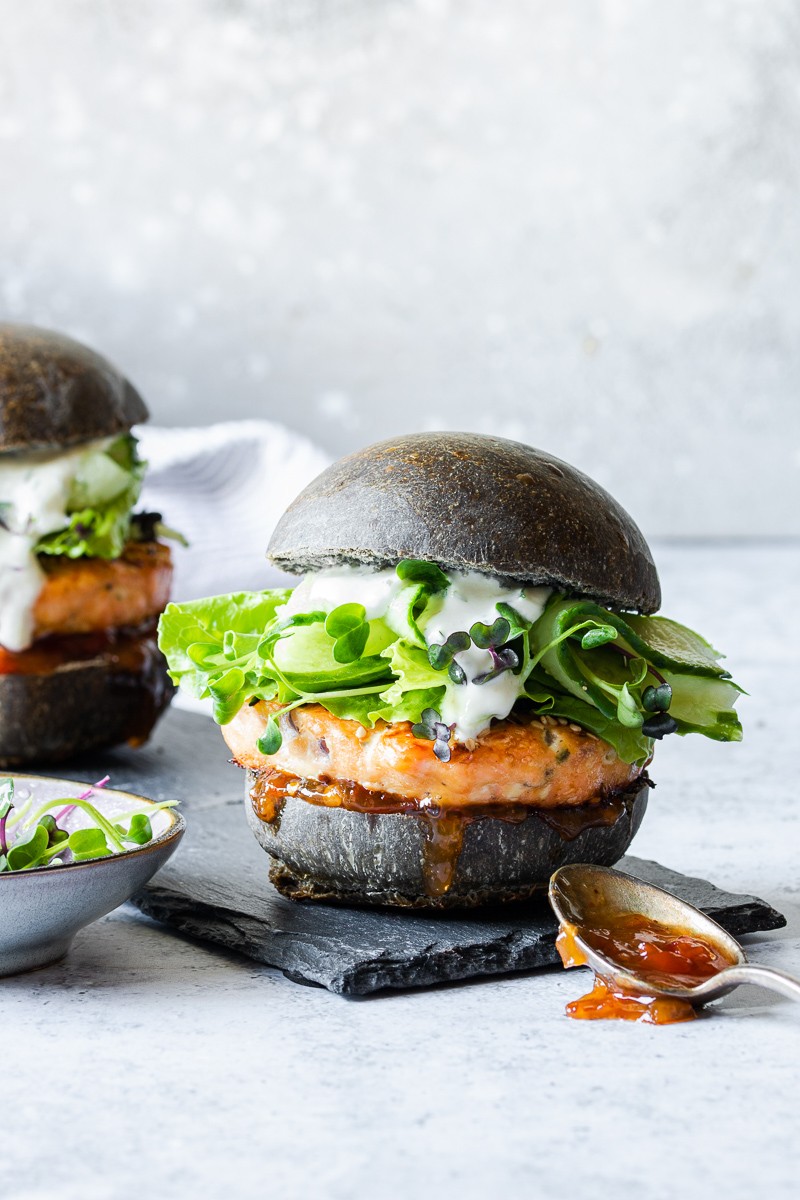 Hamburger di salmone con bun al nero di seppia, cetrioli e salsa allo yogurt