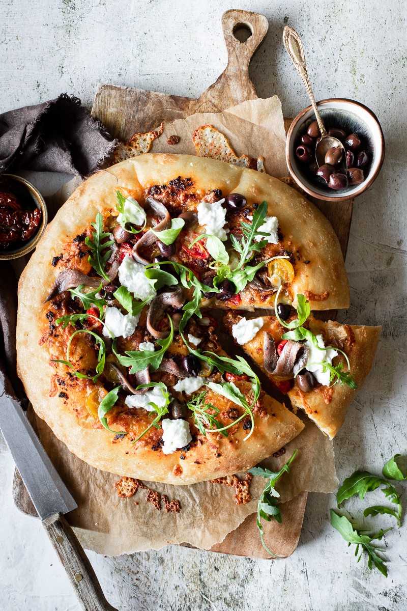 pizza con acciughe pesto di pomodorini rucola e burrata